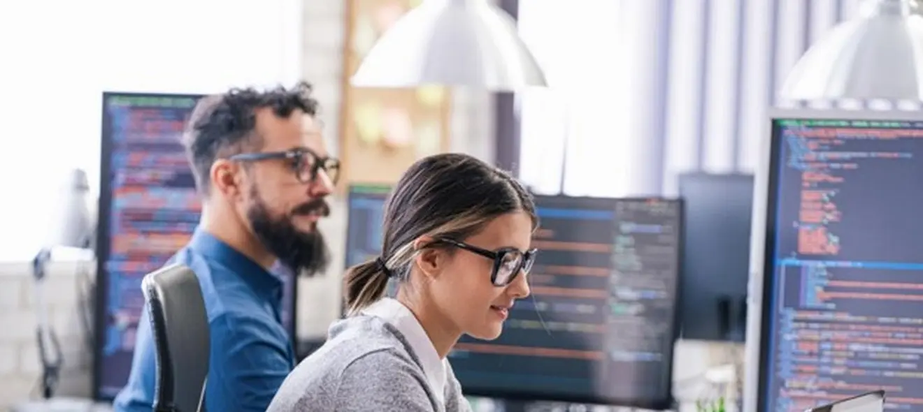 Two data scientists working on computers in an office