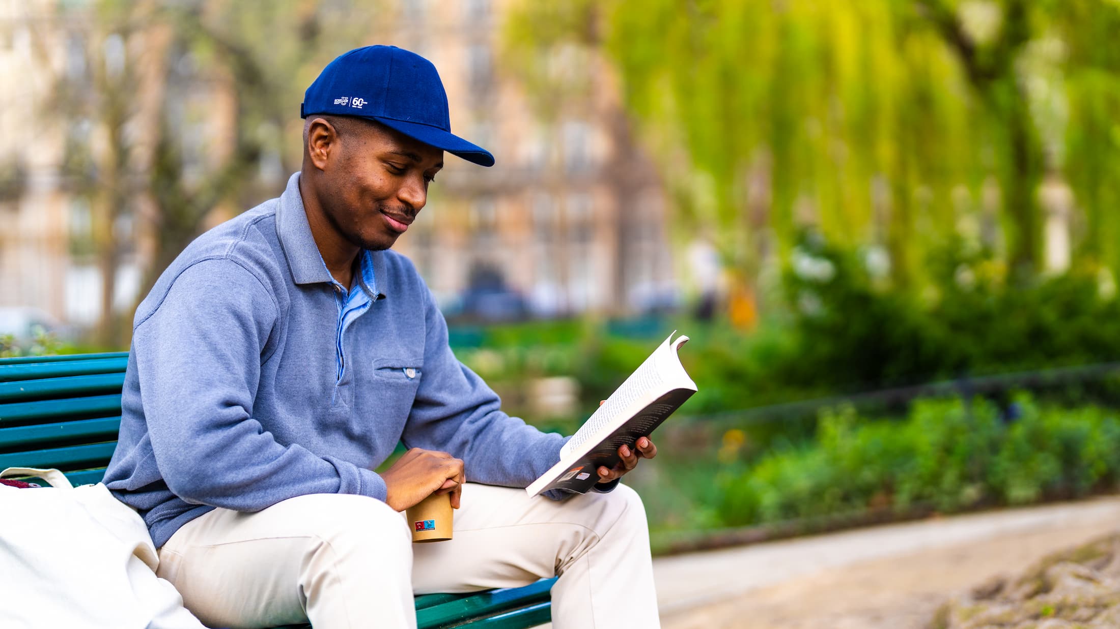 A student reading a book issued from the Schiller library in a park